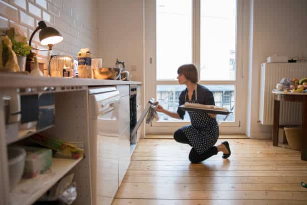 Femme qui met un plat au four dans sa cuisine